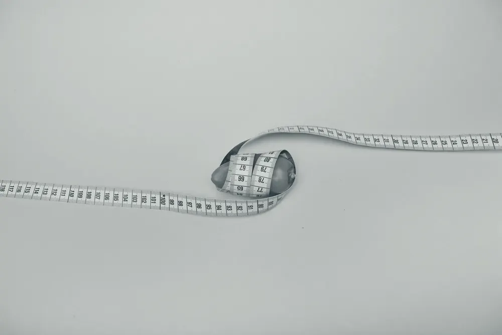 Pimentão vermelho envolto por uma fita métrica amarela, simbolizando a medição da circunferência abdominal.