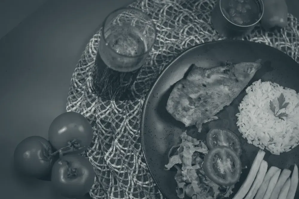 Prato com filé de peixe grelhado, arroz branco e salada de folhas com tomate, representando o equilíbrio entre proteínas, carboidratos e vegetais.