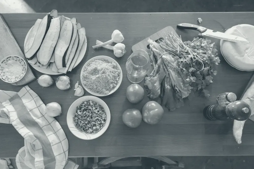 Vista de cima de alimentos frescos e ingredientes variados organizados sobre uma mesa de madeira.